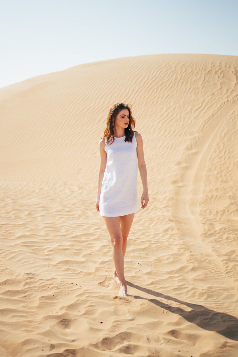 Women posing in the Dubai desert in a short white pure linen dress by Anse Linen.