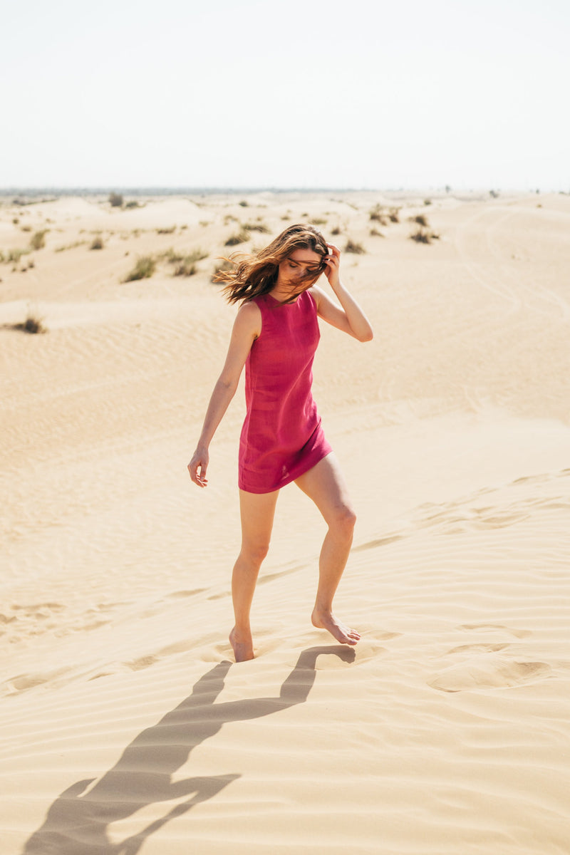 A woman wearing pink short, mini, straight summer linen dress by Anse Linen. Desert photoshoot.