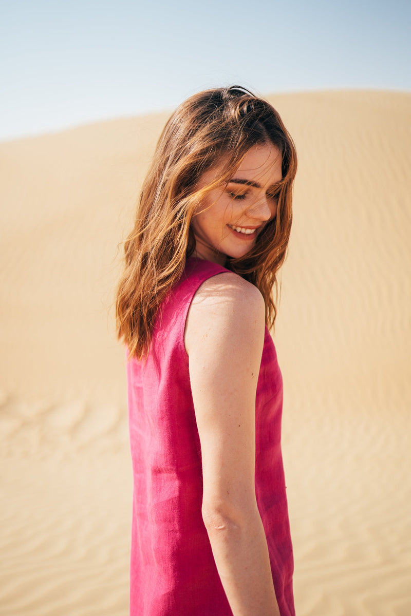 A woman wearing short linen summer dress in pink by Anse Linen. Desert photoshoot in Dubai, UAE.